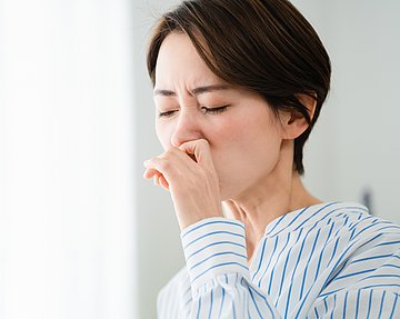 Frau reibt sich die verschnupfte Nase.