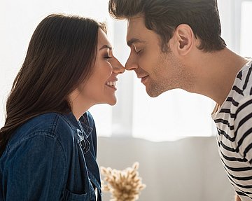 Frau und Mann, die sich an den Nasen berühren und lachen.