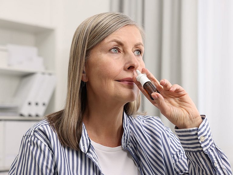 Frau benutzt ein Nasenspray. 
