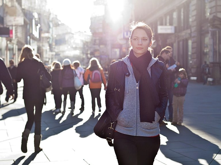 Ist eine Nasennebenhöhlenentzündung ansteckend oder besteht kein Risiko in der Öffentlichkeit? Frau läuft wegen Ansteckungsgefahr misstrauisch durch eine Stadt.